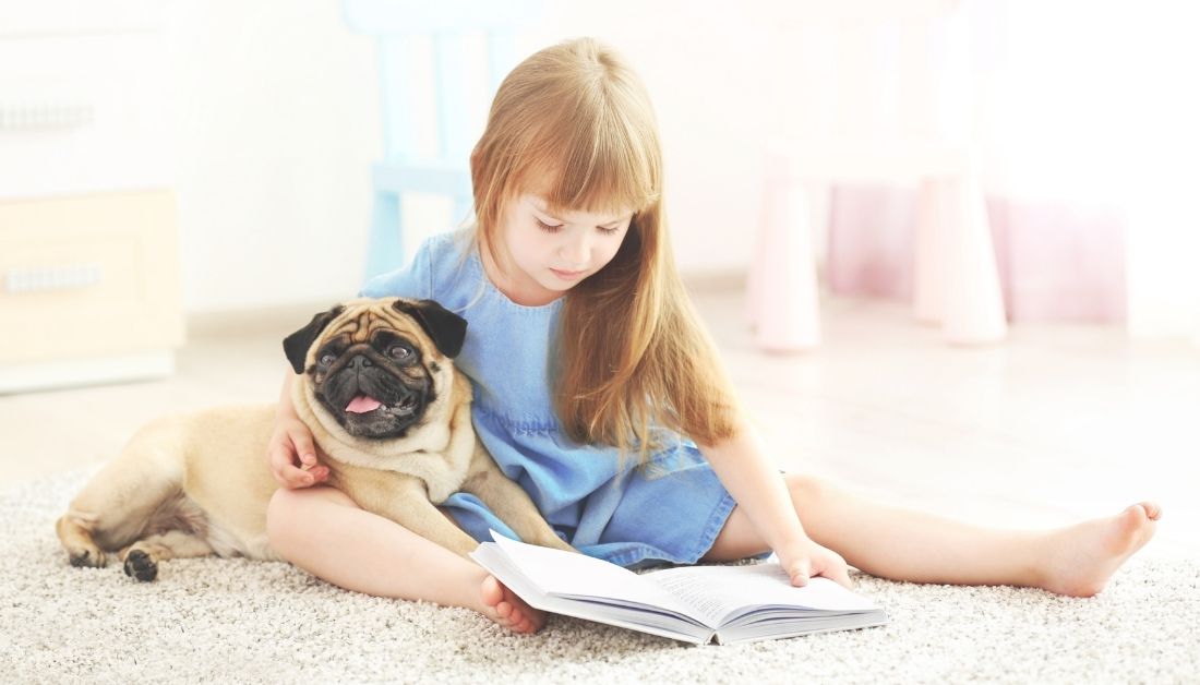 girl reading book with dog